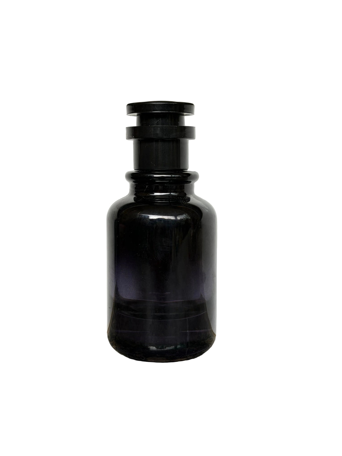 A dark amber glass bottle with a black screw cap, standing on a speckled granite countertop against a white wall.